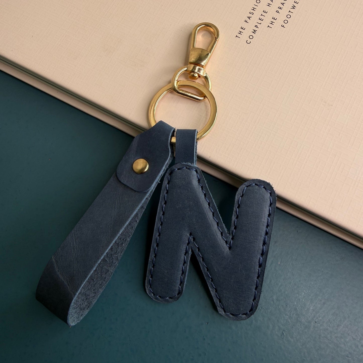 A navy blue leather letter 'N' keychain with a gold-tone lobster clasp and split ring.